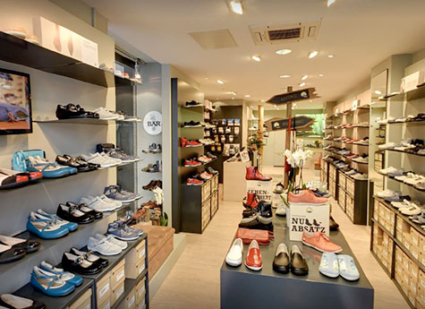 Innenansicht eines eleganten Schuhgeschäfts mit verschiedenen Schuhmodellen und stilvollen Accessoires auf Regalen und Tischen