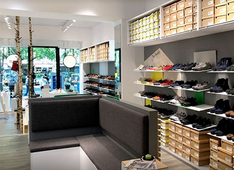 Innenansicht einer modernen Schuhboutique mit Regalen voller verschiedenfarbiger Schuhe und einer Sitzecke