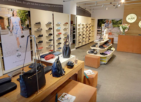 Innenansicht eines stilvollen Schuh- und Taschengeschäfts mit moderner Einrichtung und großer Produktauswahl