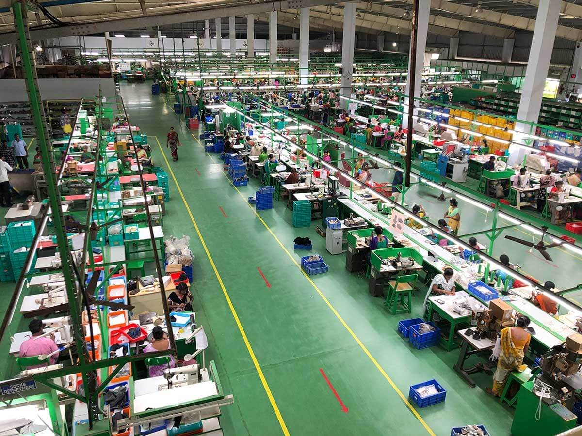 Luftaufnahme einer großen Textilfabrikhalle mit Arbeitern, die an Nähstationen arbeiten