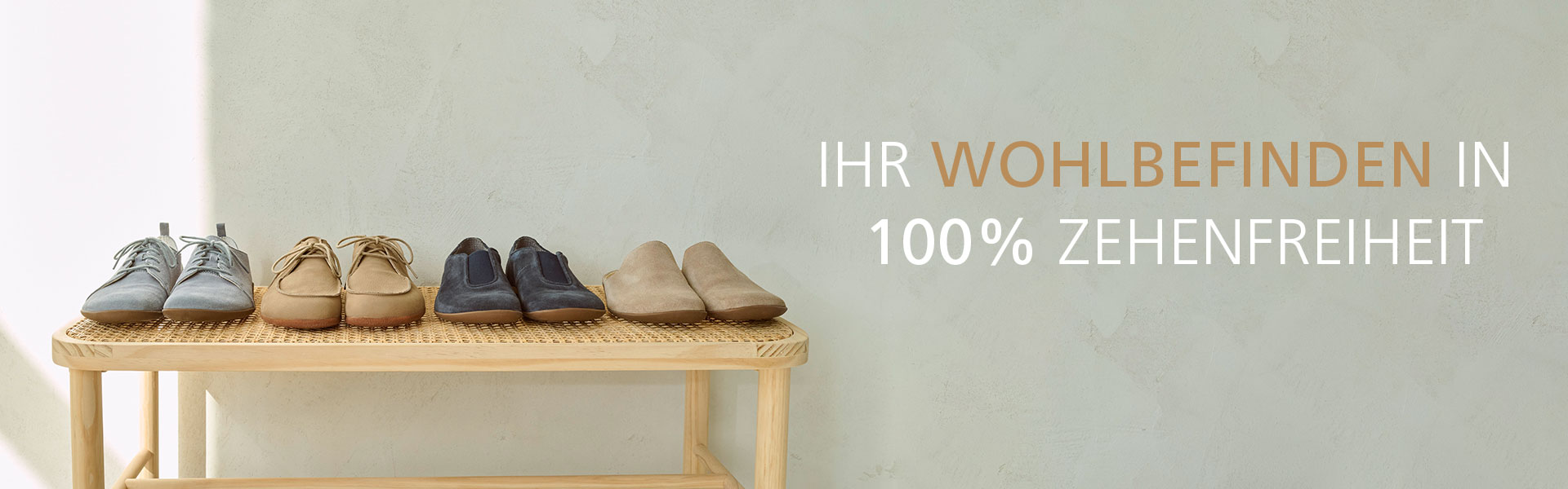 Verschiedene Paar Schuhe auf einem Regal mit dem Slogan 'Ihr Wohlbefinden in 100% Zehenfreiheit' im Hintergrund.