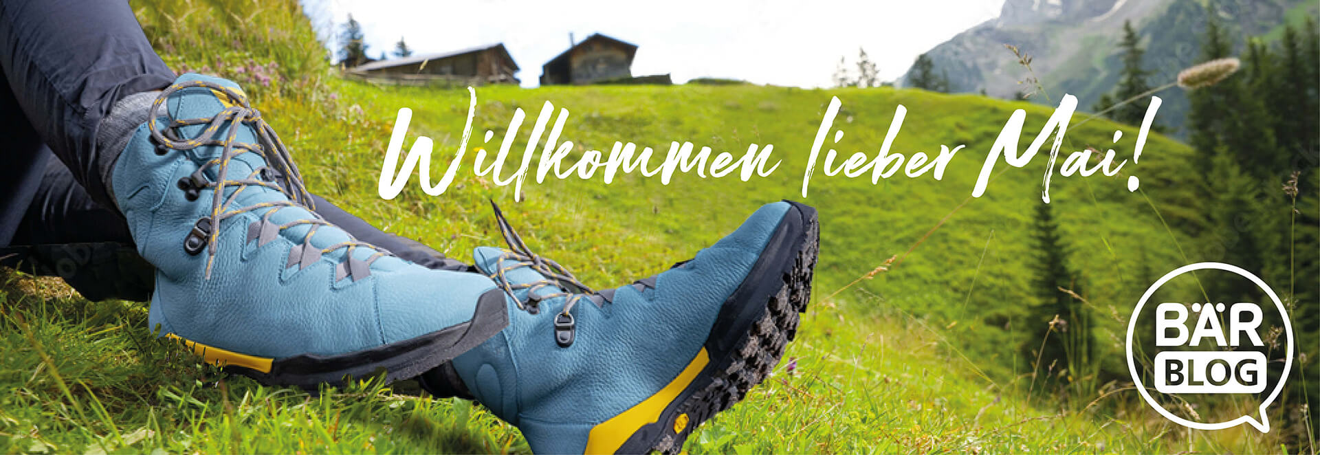 Person entspannt sich in blauen Wanderschuhen auf einer Frühlingswiese mit dem Text 'Willkommen lieber Mai' im Hintergrund