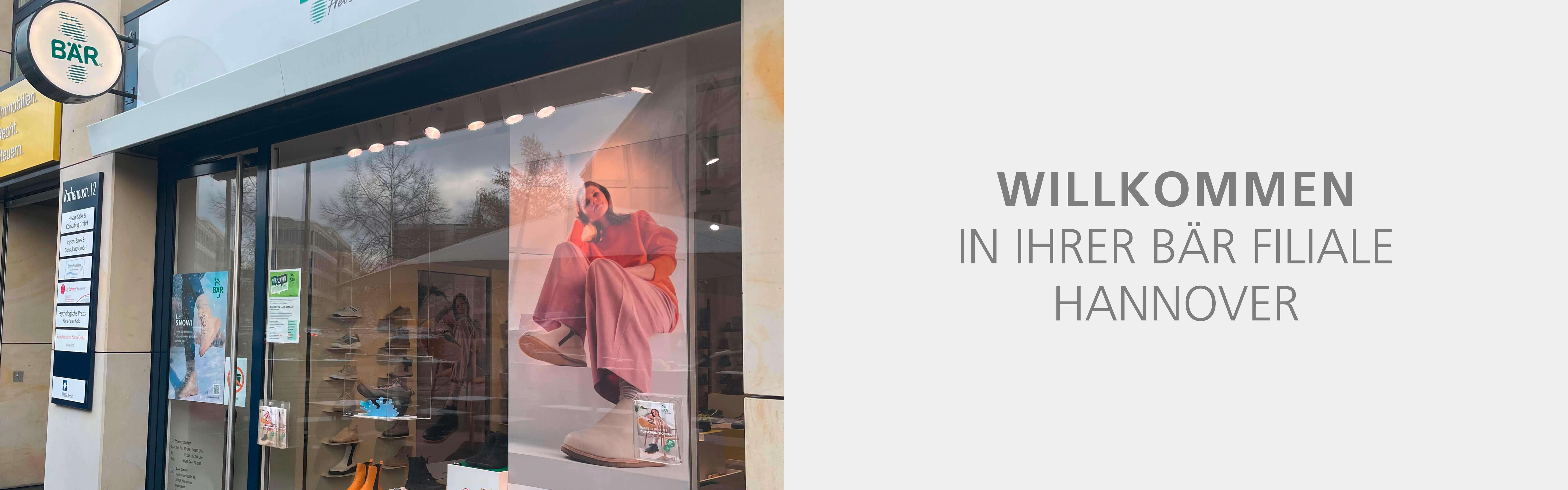 Außenansicht der BÄR Filiale in Hannover mit Schaufensterdekoration, einschließlich eines großen Fotos einer Frau in rosa Kleidung im Schaufenster.