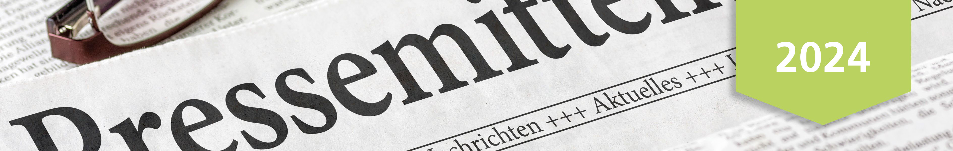 Nahaufnahme einer Zeitungsseite mit der Überschrift 'Pressemitteilung' und einem grünen Banner, das das Jahr 2024 zeigt.