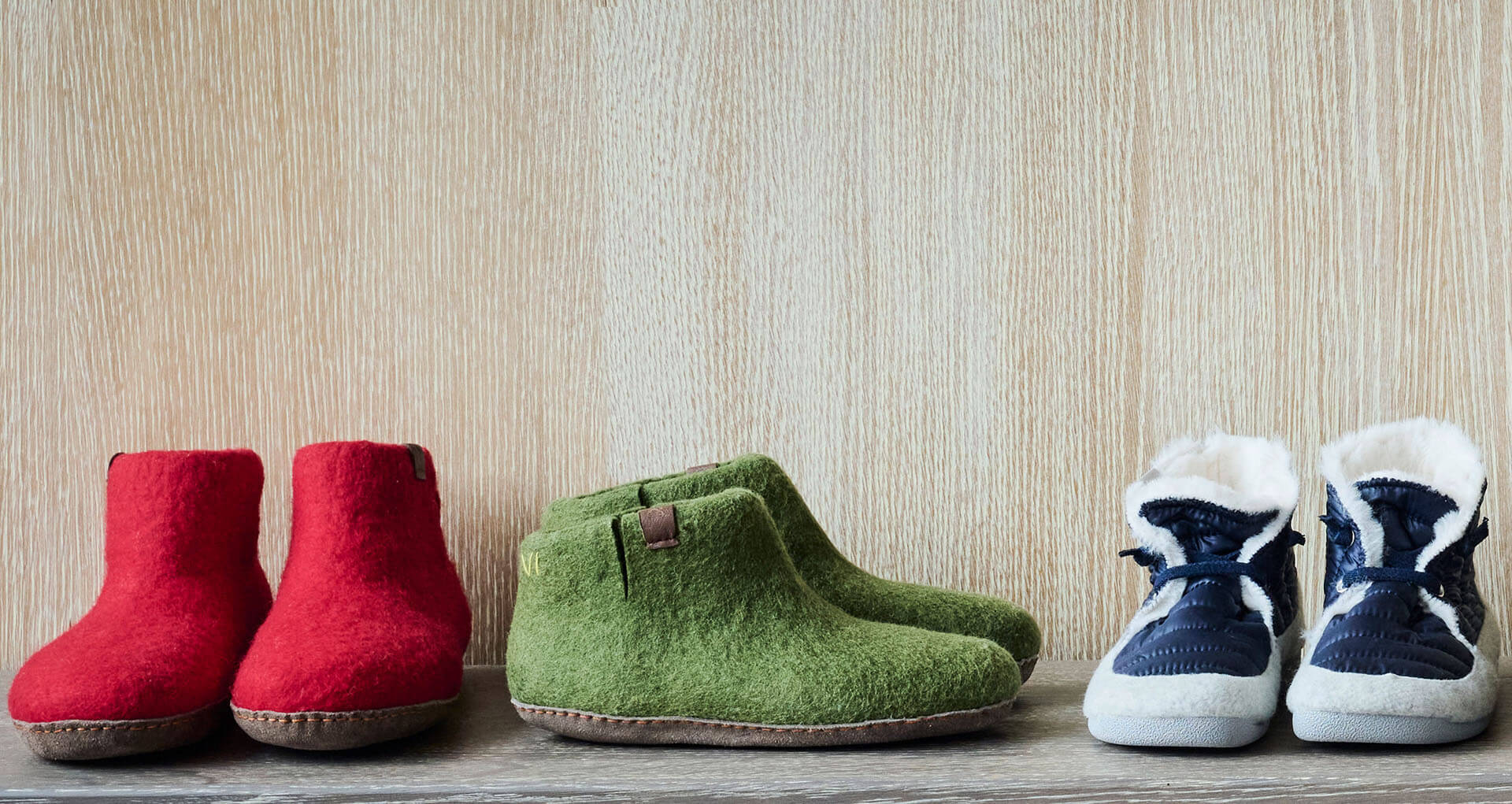 Bild von drei Paar Hausschuhen: rote Filzpantoffeln, grüne Wollhausschuhe und blaue gefütterte Hausschuhe