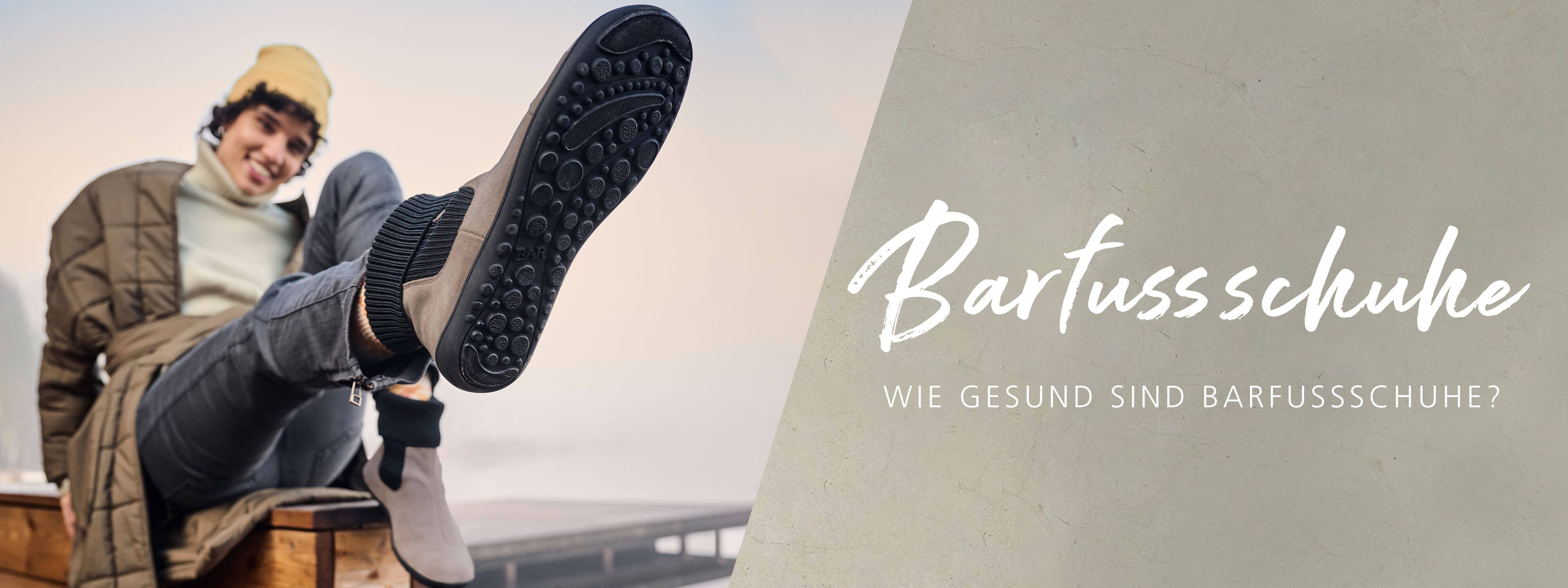 Lächelnde Person in Barfußschuhen mit Fokus auf die Sohle.