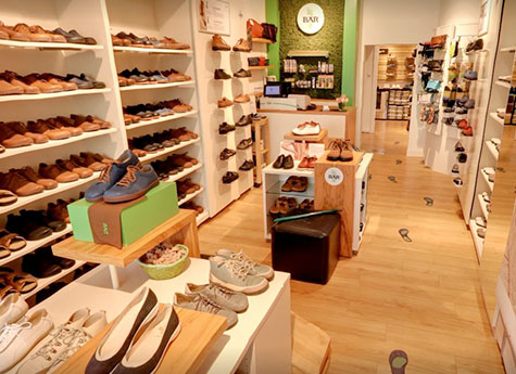 Innenansicht eines Schuhladens mit zahlreichen Regalen voller Schuhe für Damen und Herren, gemütliche Atmosphäre mit Holzboden und dekorativen Elementen