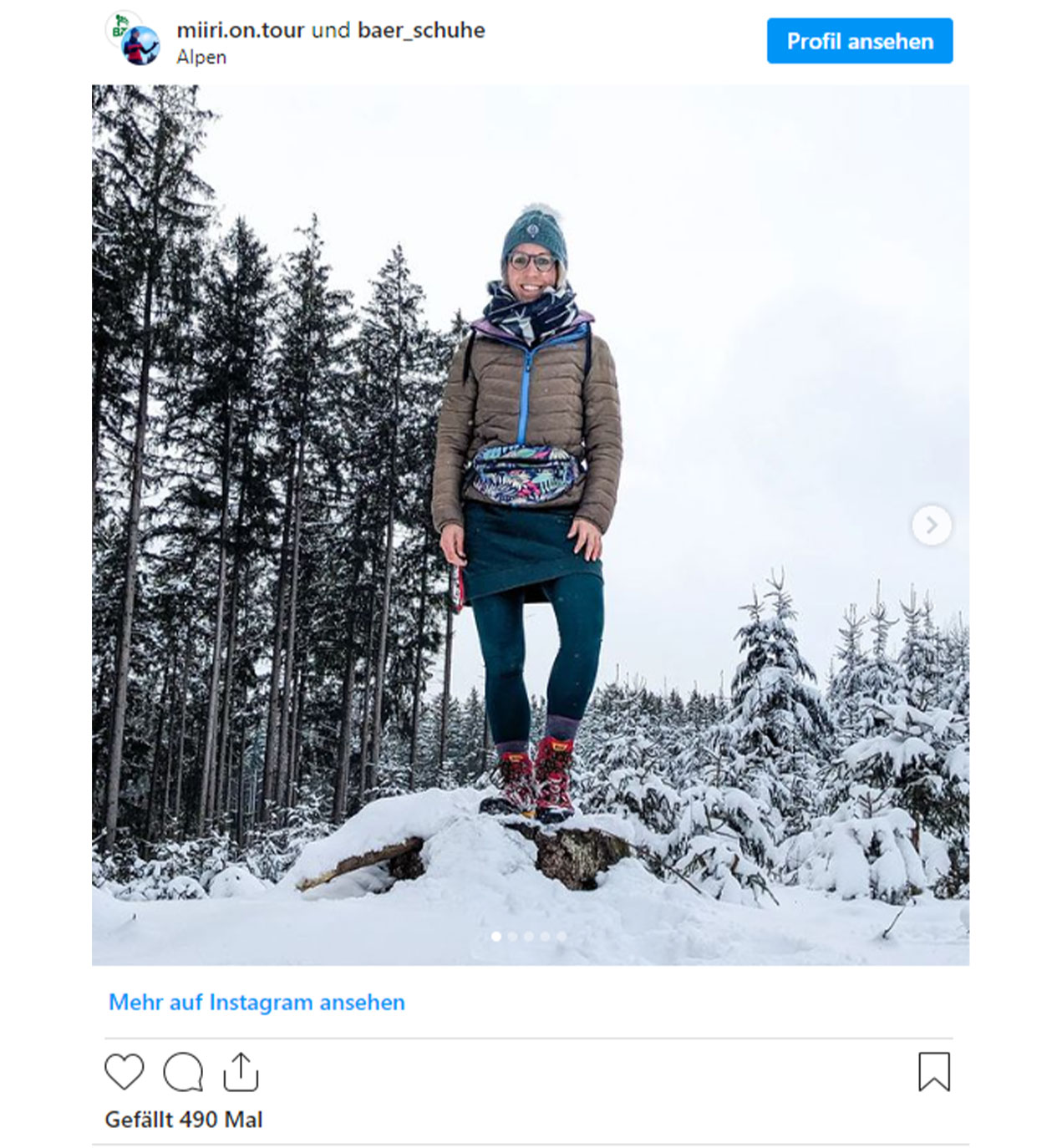 Person in Outdoor-Bekleidung bei einer Wanderung in den schneebedeckten Alpen, umgeben von einem winterlichen Wald