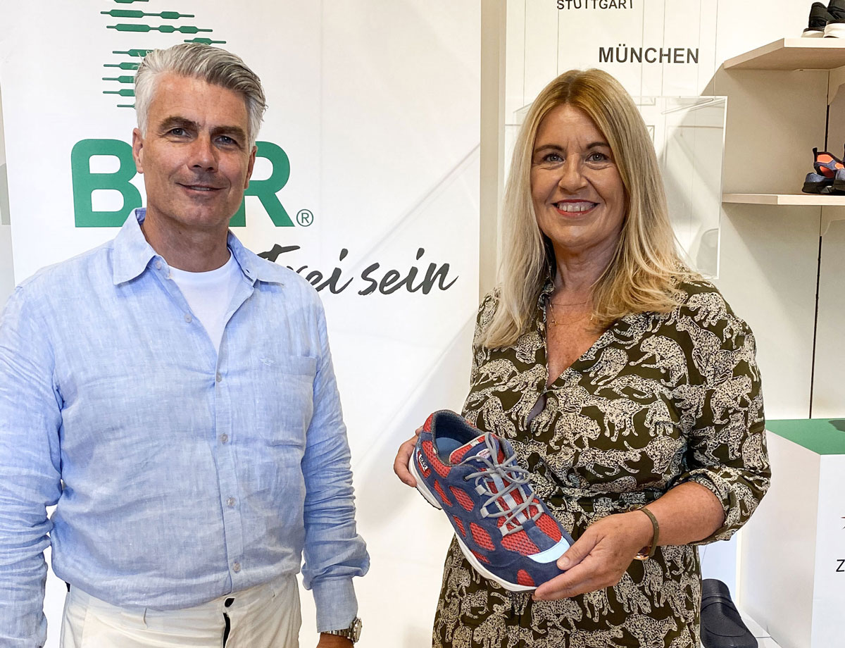 Ein Mann und eine Frau in einem Schuhgeschäft, die Frau hält einen bunten Sneaker in der Hand.