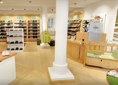 Innenansicht einer Schuhboutique mit verschiedenen Schuhregalen und einer gemütlichen Sitzecke.