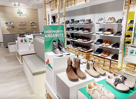 Innenansicht eines Schuhgeschäfts mit Eröffnungsangeboten, verschiedenen Stilen und Farben auf Regalen ausgestellt.